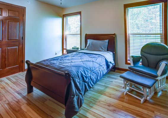 A private resident room with a bed and rocking chair