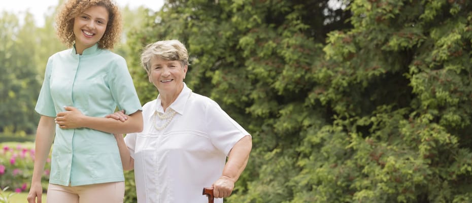 Staff assisting a resident in a garden setting