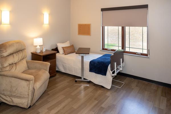 A cozy resident room with a bed and armchair