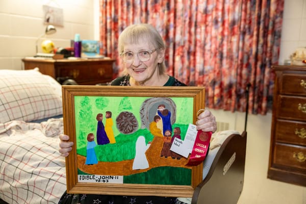 Resident proudly displaying her artwork in a room