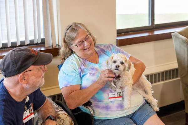 Residents enjoying time with a small dog in a common area