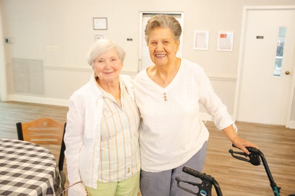 Two senior women smiling together in a common area