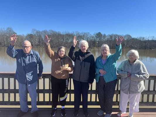 Residents waving by a lake on a sunny day