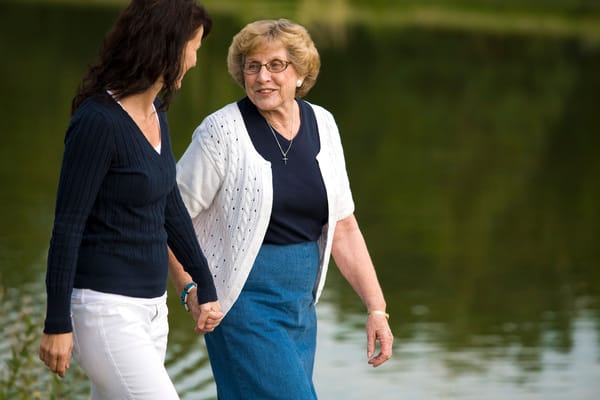Two women walking by a serene lake