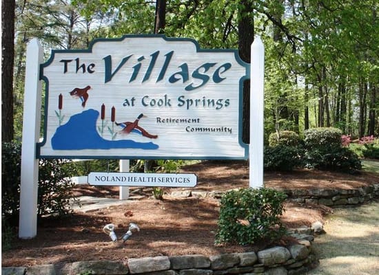 Sign for The Village at Cook Springs outside in a garden