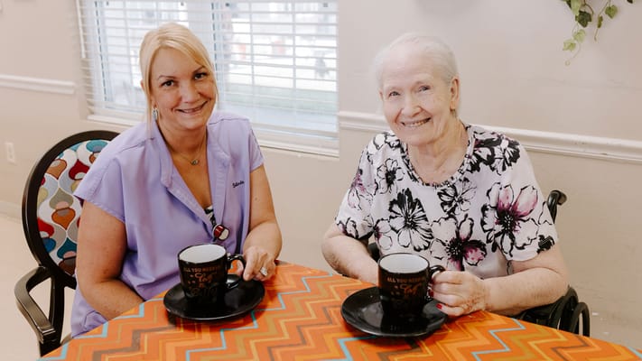 Resident and staff enjoying refreshments at a table