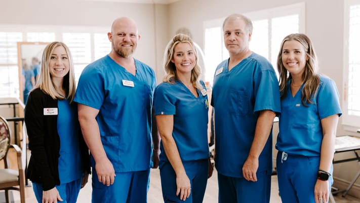 Five staff members posing in blue scrubs