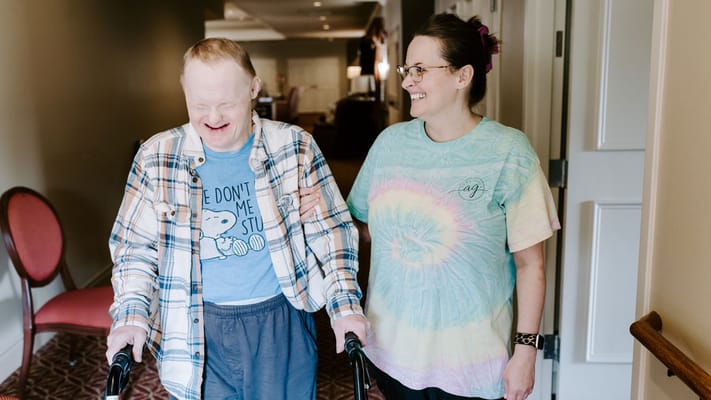 Resident enjoying time with staff in a hallway
