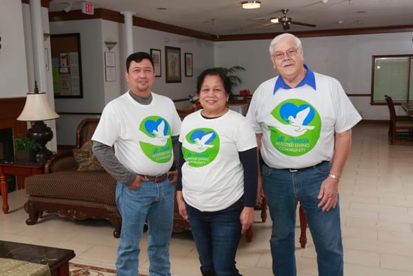 Three staff members in a common area wearing facility shirts