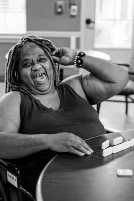 Resident smiling while playing dominoes indoors