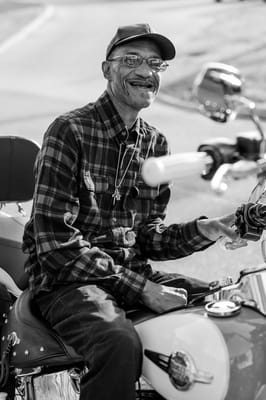A senior man smiling while sitting on a motorcycle