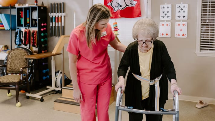 Staff assisting a resident with a walker in an activity room