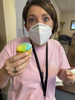 Staff member holding a colorful cupcake in a common area