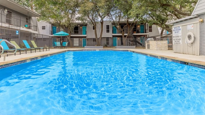 Swimming pool surrounded by trees and lounge chairs