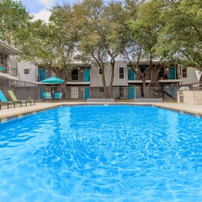 A swimming pool surrounded by trees and buildings