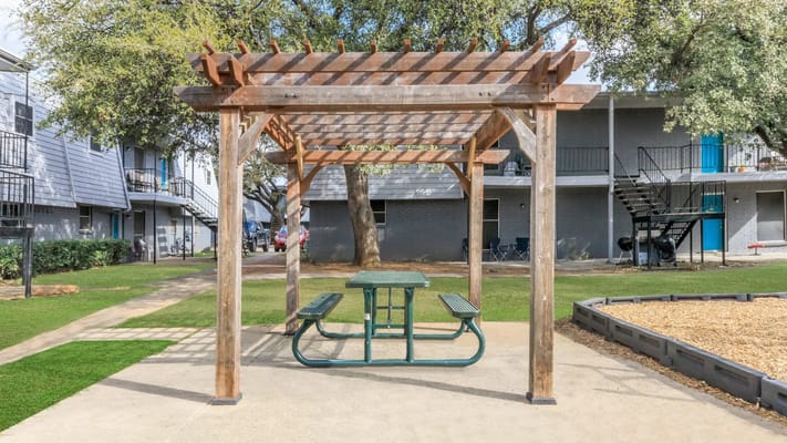 Outdoor picnic area with a wooden pergola and table
