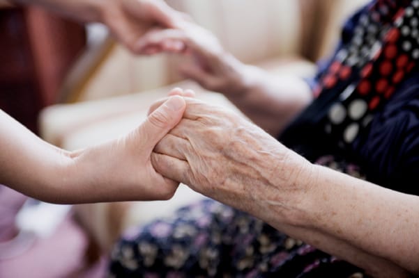 Hands of a caregiver and a resident holding each other