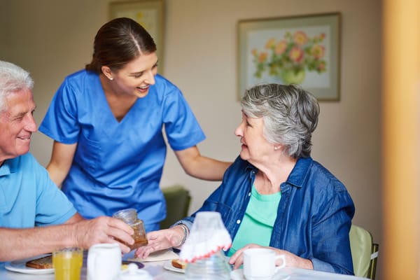 A caregiver assisting seniors during a meal