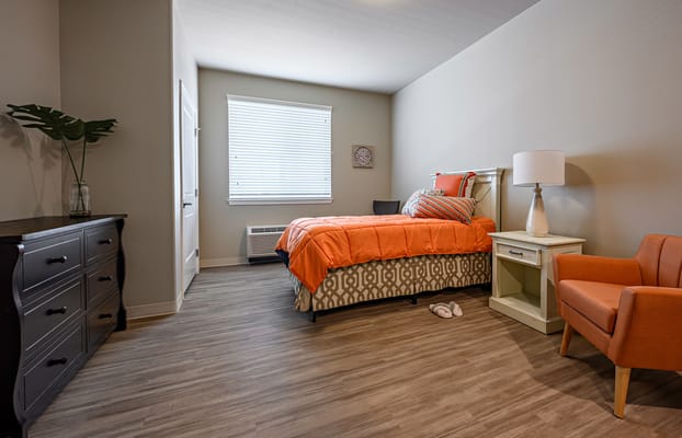 A bright and inviting resident room with orange accents