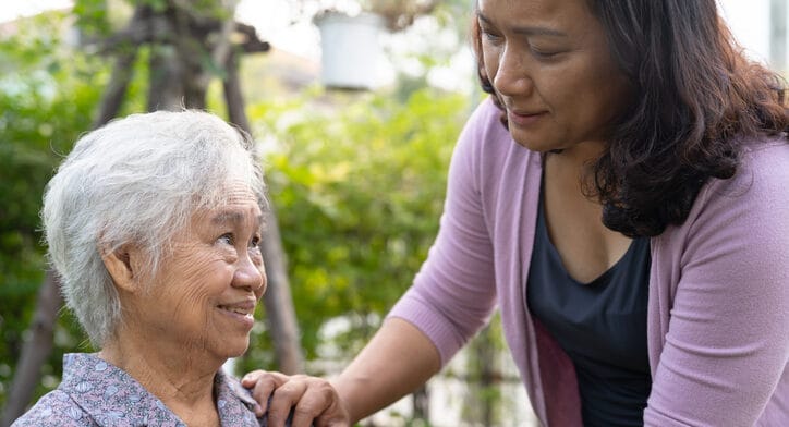 Caregiver interacting with a smiling senior in a garden
