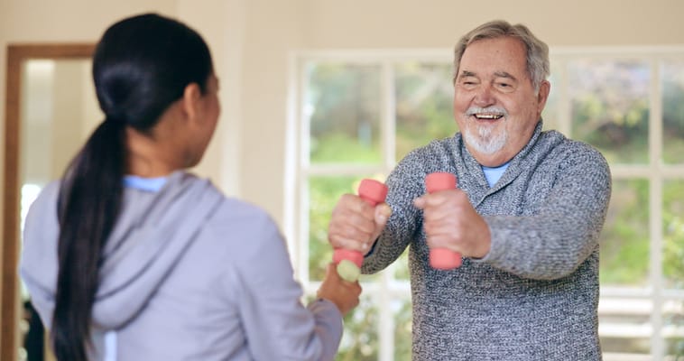 Senior exercising with a staff member in a bright space
