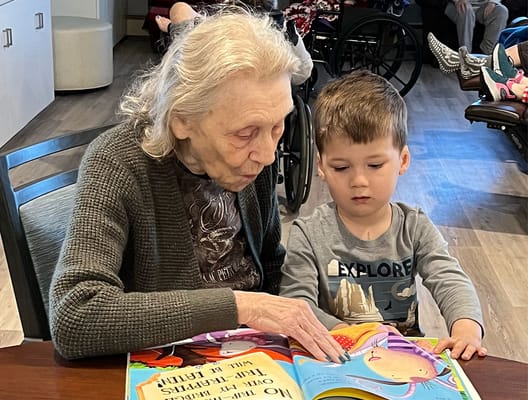 An elderly woman reading with a young boy