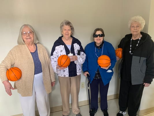 Four residents holding basketballs in an indoor setting