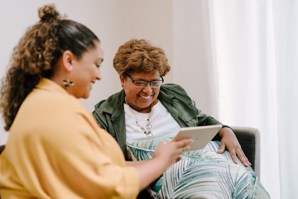 Two women sharing a moment while looking at a tablet
