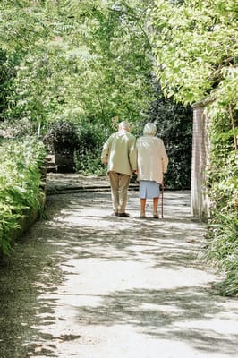 Elderly couple walking together in a lush garden