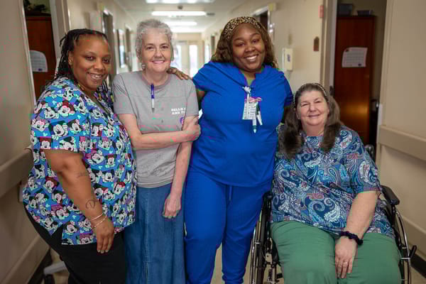 Staff and residents smiling together in a hallway