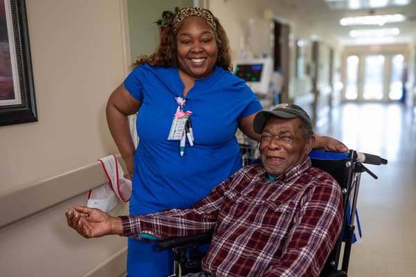 Staff member smiling with a resident in a hallway