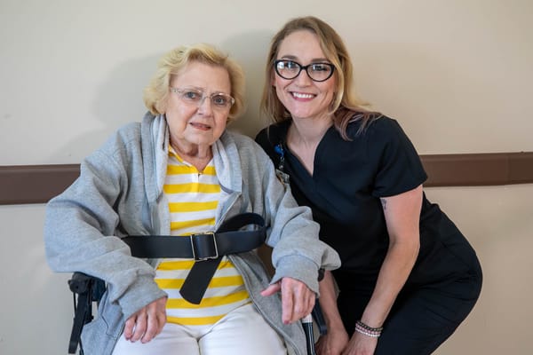 Resident smiling with staff member in a facility room