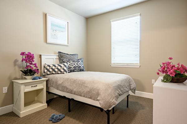 A cozy resident room with a bed and flowers