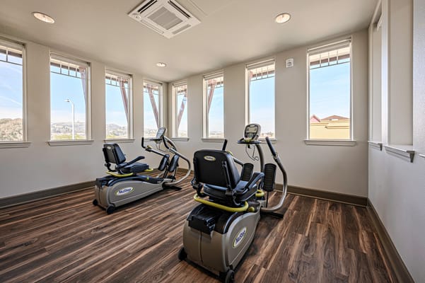 Bright fitness area with exercise equipment and large windows