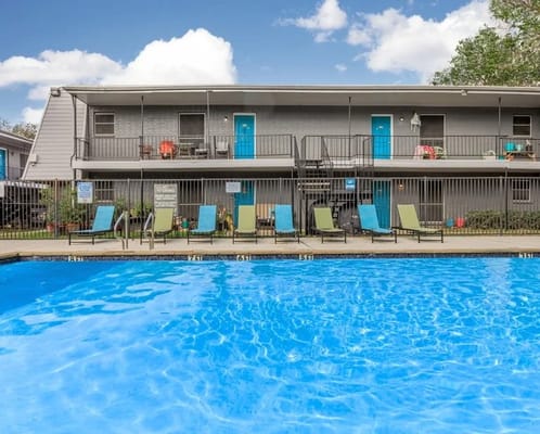 Outdoor pool area with lounge chairs and building in background