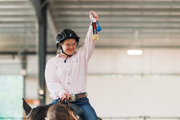 A resident celebrating with a gold medal on horseback