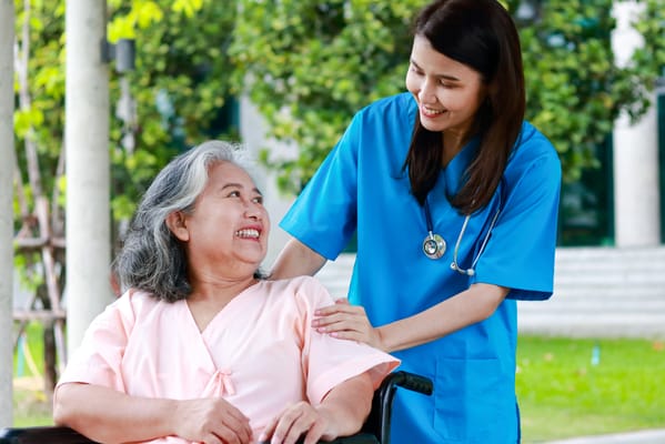 Caregiver smiling with resident outdoors.