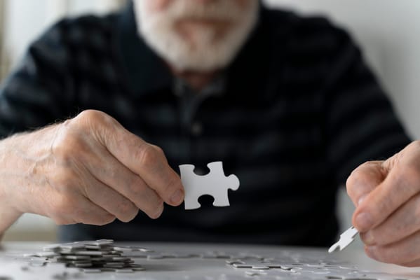 An elderly man working on a puzzle indoors