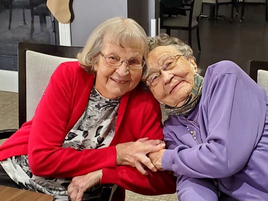 Two residents smiling and embracing in a common area