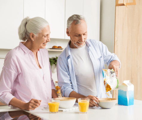 Two seniors preparing breakfast together in a bright kitchen