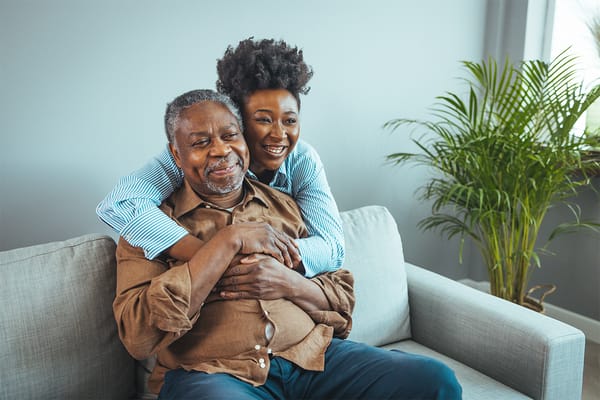 Elderly man embracing a caregiver in a cozy common area