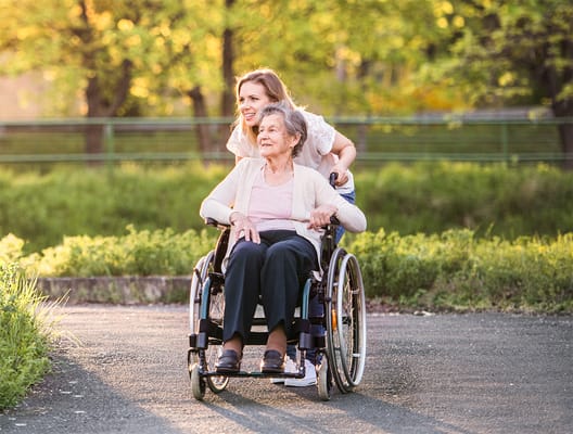A caregiver pushing a resident in a wheelchair outdoors