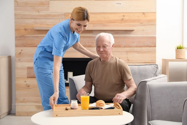 Staff serving breakfast to a resident in a common area