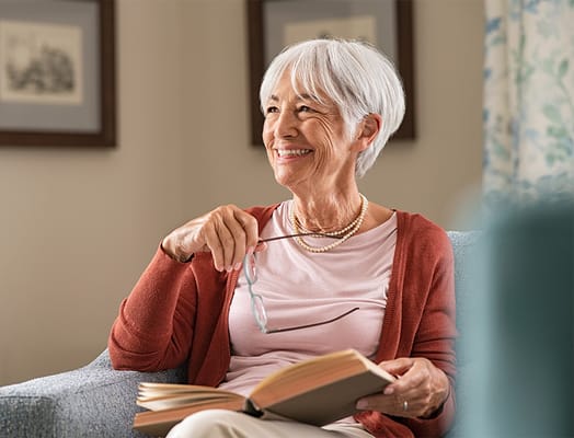 Senior resident reading a book in a cozy chair