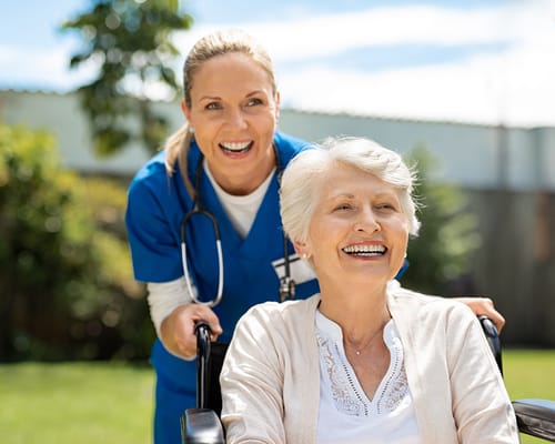 A caregiver smiling with a resident in a garden