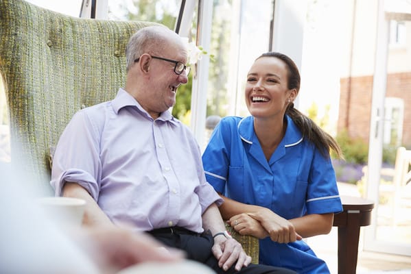 Caregiver laughing with a resident in a bright setting