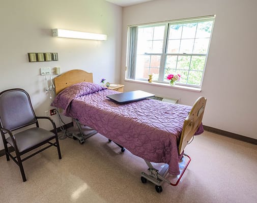 Private resident room with a hospital bed and chair