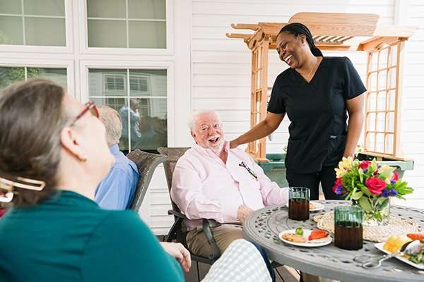 Residents enjoying a meal outside with staff interaction