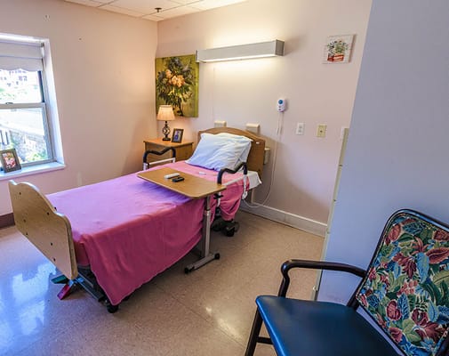 A private resident room with a bed and chair