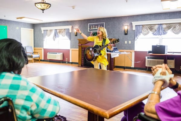 A musician performing for residents in an activity room